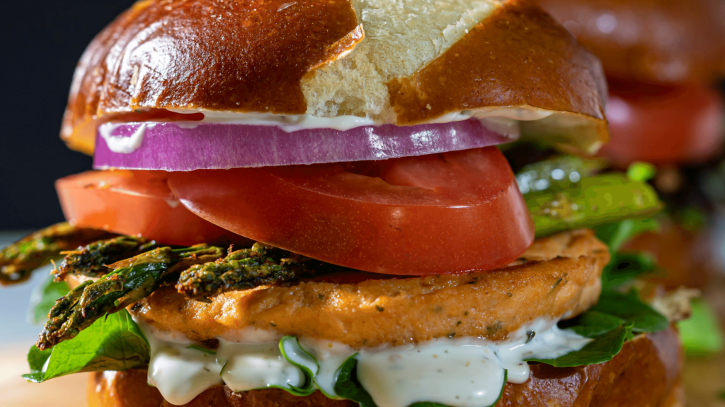 salmon burger topped with asparagus, tomato, red onion, and creamy sauce